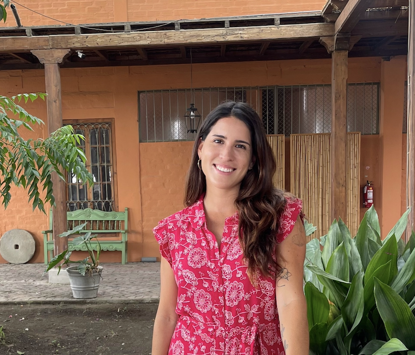 Mariel Sifuentes sonriendo frente a una casa de tonos terracota